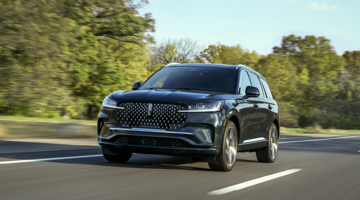 A 2025 Lincoln Black Label Aviator® SUV is being driven down a road lined with trees. | Vance Lincoln in Miami OK