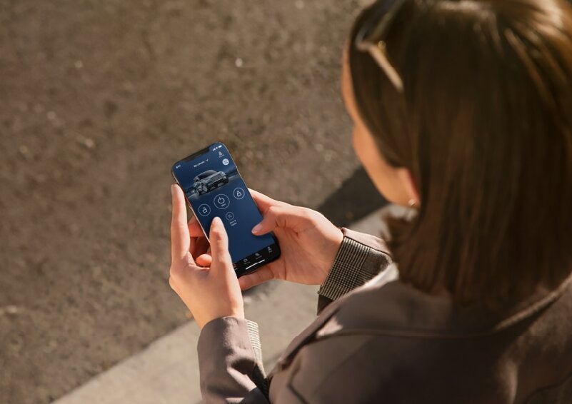 A person is shown interacting with a smartphone to connect to a Lincoln vehicle via the Lincoln Way® App. | Vance Lincoln in Miami OK