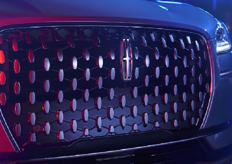 The grille of a 2025 Lincoln Corsair® SUV reflects neon light at night. | Vance Lincoln in Miami OK