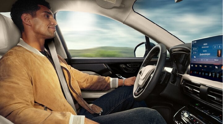 A person is shown using Lincoln BlueCruise hands-free highway driving technology on a divided highway called a Hands-Free Blue Zone. | Vance Lincoln in Miami OK