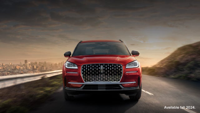 A 2025 red Lincoln Corsair® SUV is being driven down a road at sunset. | Vance Lincoln in Miami OK