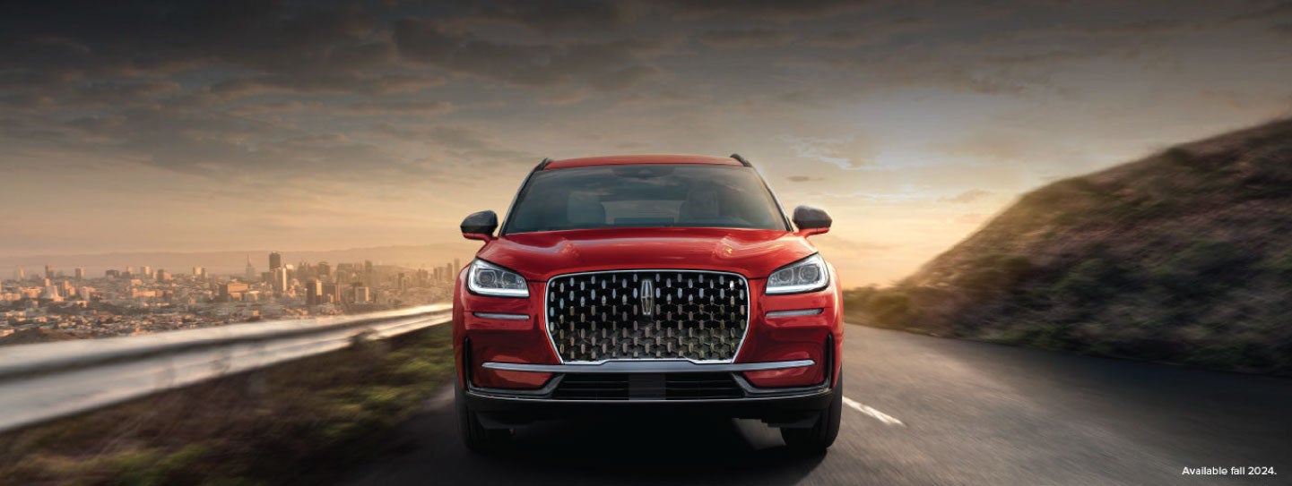 A 2025 red Lincoln Corsair® SUV is being driven down a road at sunset. | Vance Lincoln in Miami OK