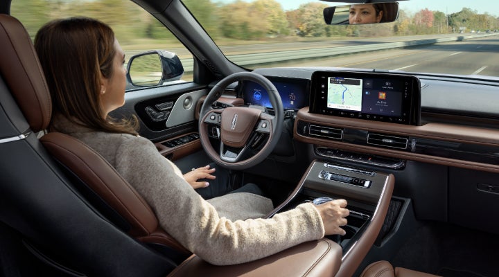 A 2026 Lincoln Aviator® SUV is being driven hands-free on a highway near a forest | Vance Lincoln in Miami OK