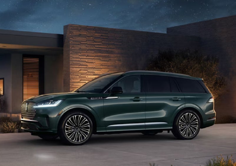 A green 2027 Lincoln Aviator® SUV is parked outside a contemporary home. | Vance Lincoln in Miami OK