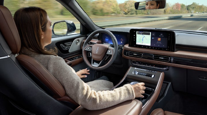 A 2027 Lincoln Aviator® SUV is being driven hands-free on a highway lined with trees. | Vance Lincoln in Miami OK