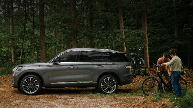 A father and son load e-bikes on a bike rack attached to a 2027 Lincoln Aviator® SUV. | Vance Lincoln in Miami OK