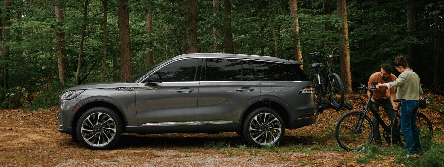 A father and son load e-bikes on a bike rack attached to a 2027 Lincoln Aviator® SUV. | Vance Lincoln in Miami OK